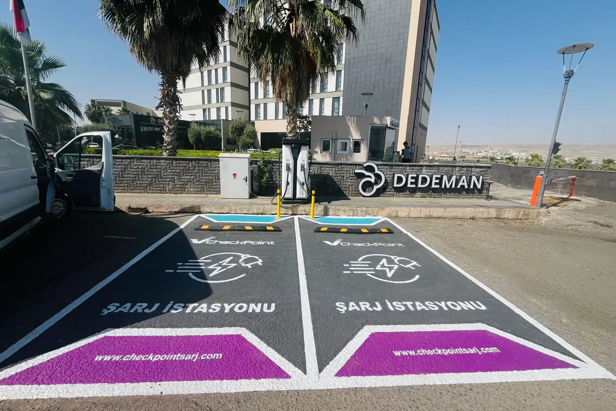 Dedeman Hotel otoparkında Checkpoint marka çizgileriyle ayrılmış iki şarj yeri ve DC şarj ünitesi